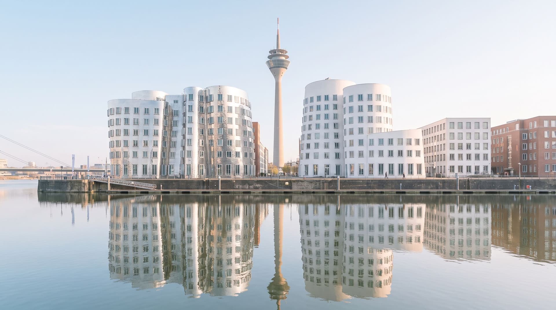 Gehry-Bauten im Düsseldorfer Medienhafen mit dem Rheinturm, gespiegelt im Hafenbecken